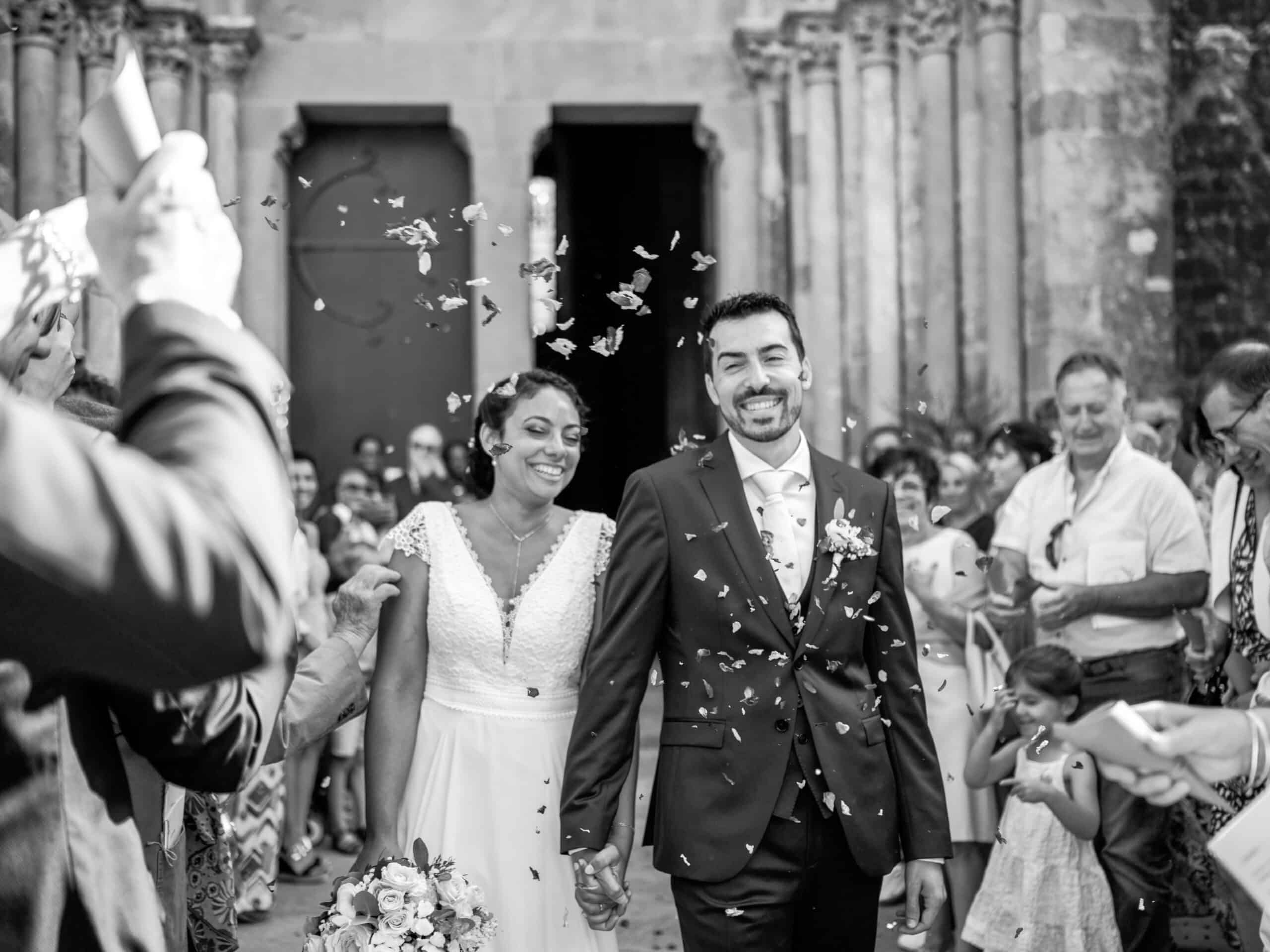 Mariage Flora & Benjamin, Sortie de la Basilique St Nazaire, Cité de Carcassonne, Aude. Jeunes mariés qui sortent de l'église sous une pluie de fleurs séchées
