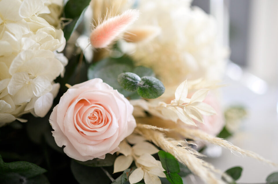 Bouquet composé de roses rose pâle, de fleurs séchées et de branches eucalyptus.