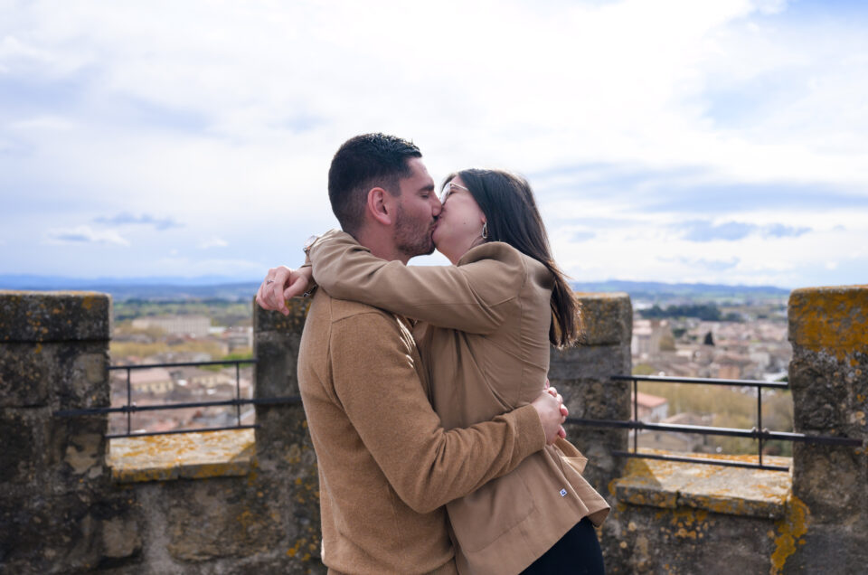 photo de couple qui s'embrasse, en haut du clocher de l'église Saint Vincent à Carcassonne, centre-ville, Bastide Saint Louis. il y a un beau ciel bleu et une vue sur les Pyrénées.