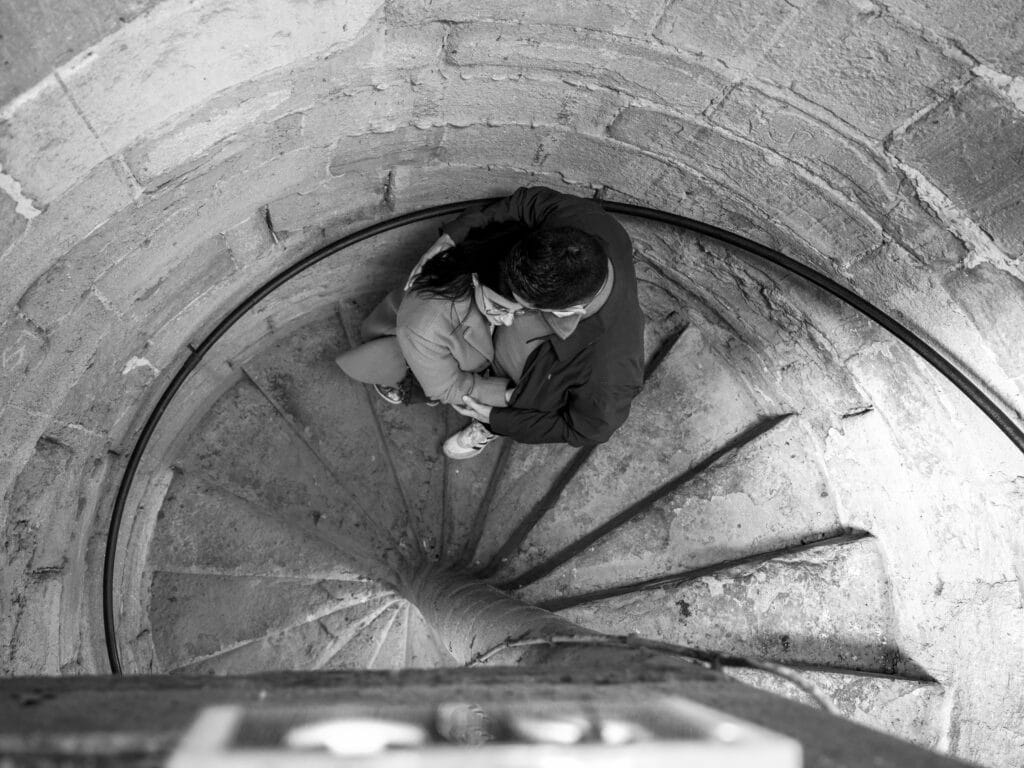 photo de couple prise en haut de l'escalier du Clocher de l'Eglise Saint Vincent, en Bastide Saint louis. Centre ville de Carcassonne. Le couple est enlacé.