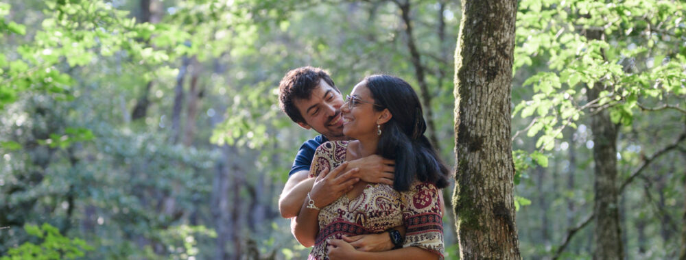 Séance photo de couple à la Rigole, dans la Montagne Noire. Ils sont enlacés dans les bras l'un de l'autre et se sourient.