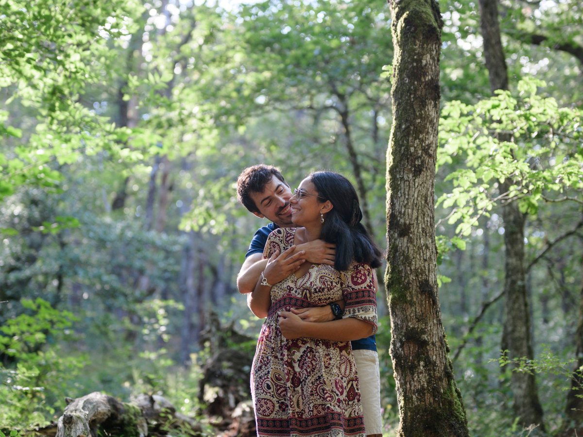 Séance photo de couple à la Rigole, dans la Montagne Noire. Ils sont enlacés dans les bras l'un de l'autre et se sourient.