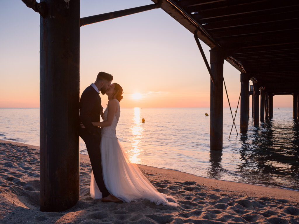 Photos de couple au lever de soleil à la plage. Day after ponton Leucate. Elle porte une robe Carrière mariage à Villefranche de Lauragais