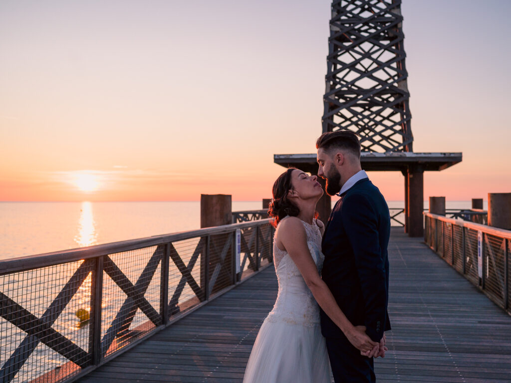 Photos de couple au lever de soleil à la plage. Day after ponton Leucate. Elle porte une robe Carrière mariage à Villefranche de Lauragais