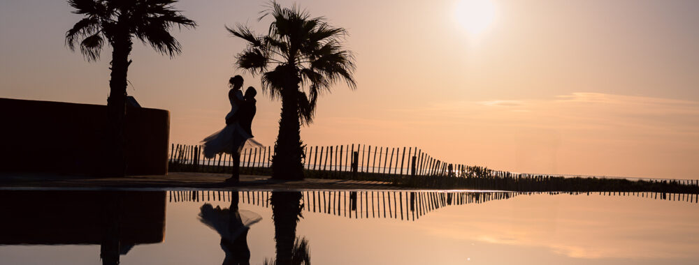 Photos de couple au lever de soleil à la plage. Day after miroir d'eau à Leucate. Elle porte une robe Carrière mariage à Villefranche de Lauragais. photo en ombres chinoises