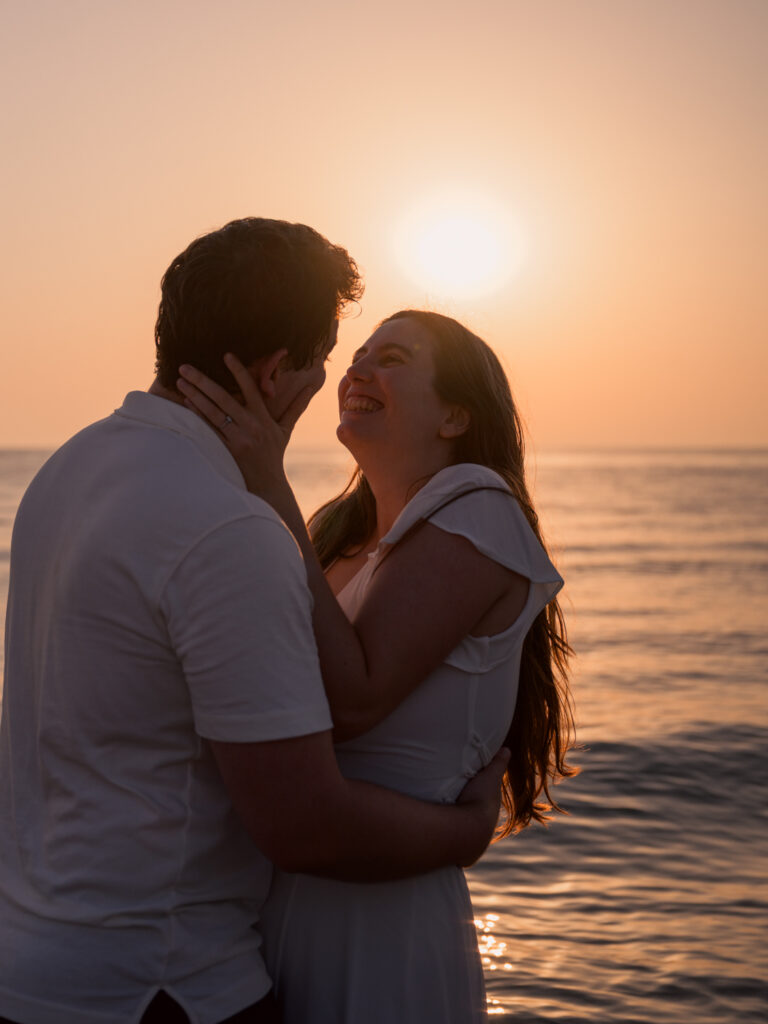 Photos de fiançailles au bord de la mer : la séance de Claire & Luc à Leucate. Séance engagement au lever de soleil au ponton de Leucate. Robe : Aym studio. Bague de fiançailles : Deloison Paris.
