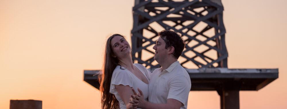 Photos de fiançailles au bord de la mer : la séance de Claire & Luc à Leucate. Séance engagement au lever de soleil au ponton de Leucate. Robe : Aym studio. Bague de fiançailles : Deloison Paris.