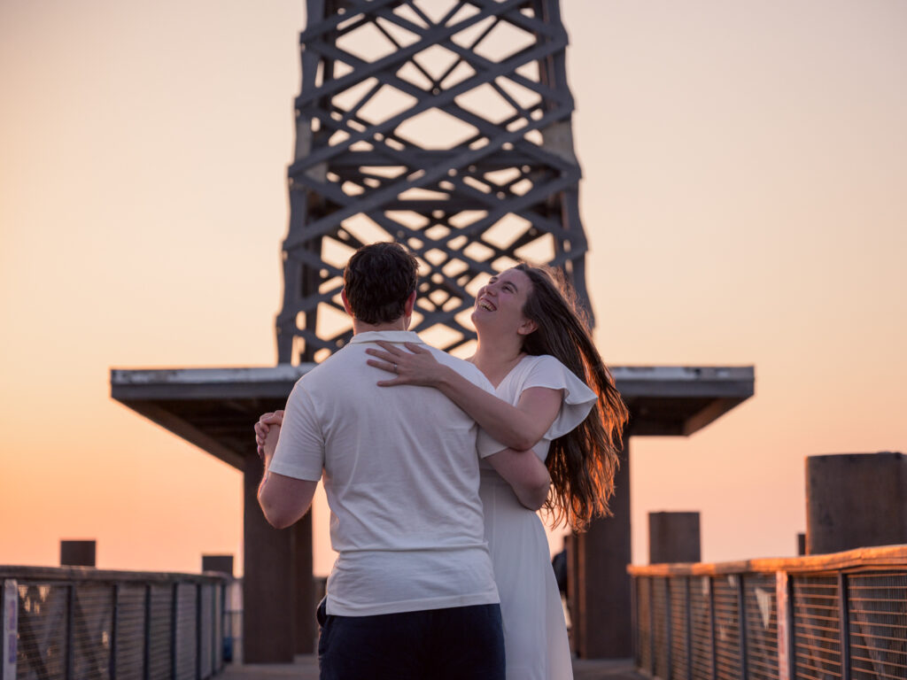 Photos de fiançailles au bord de la mer : la séance de Claire & Luc à Leucate. Séance engagement au lever de soleil au ponton de Leucate. Robe : Aym studio. Bague de fiançailles : Deloison Paris.